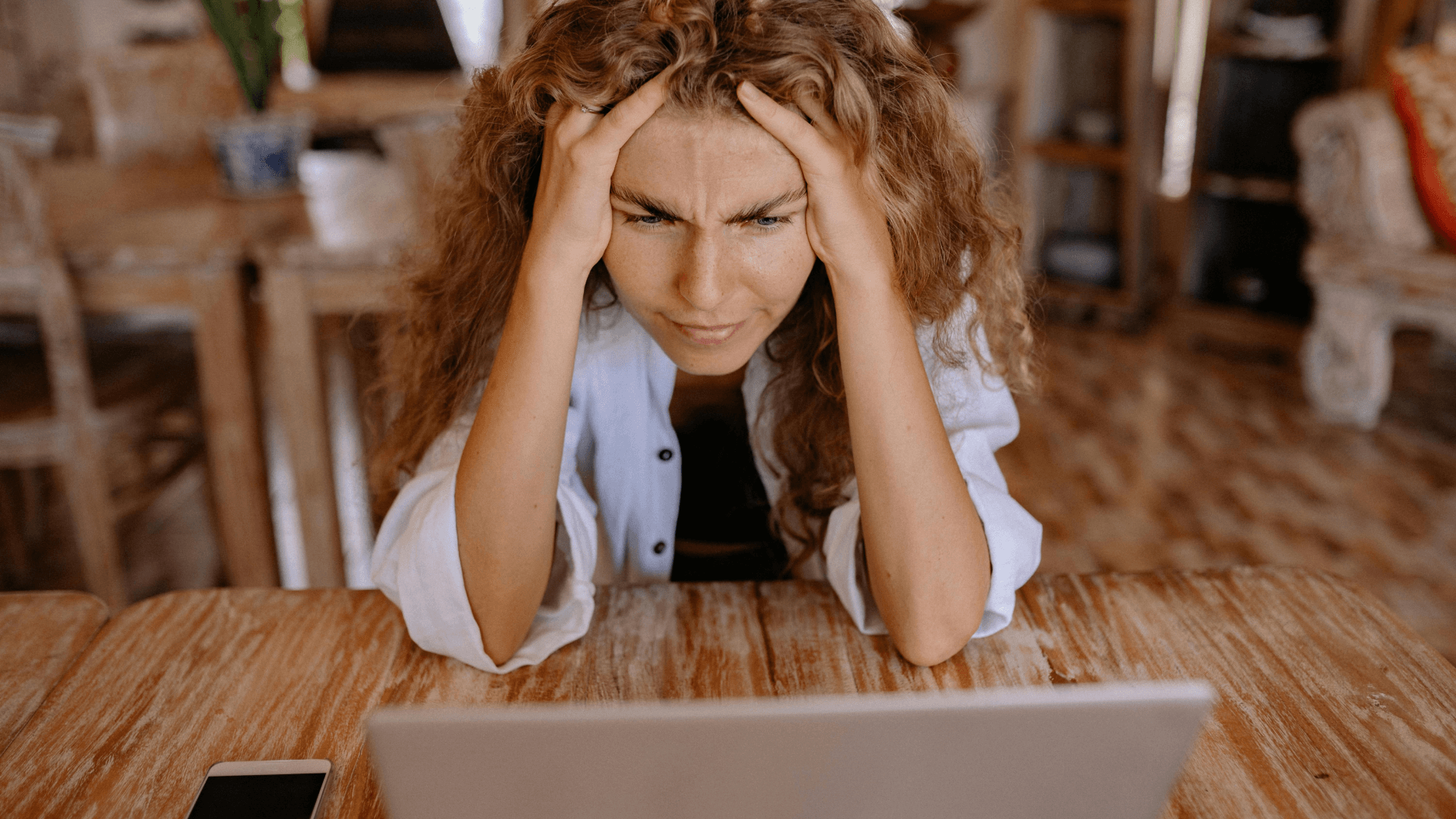 a stressed and confused women with her hand on her head looking at a computer