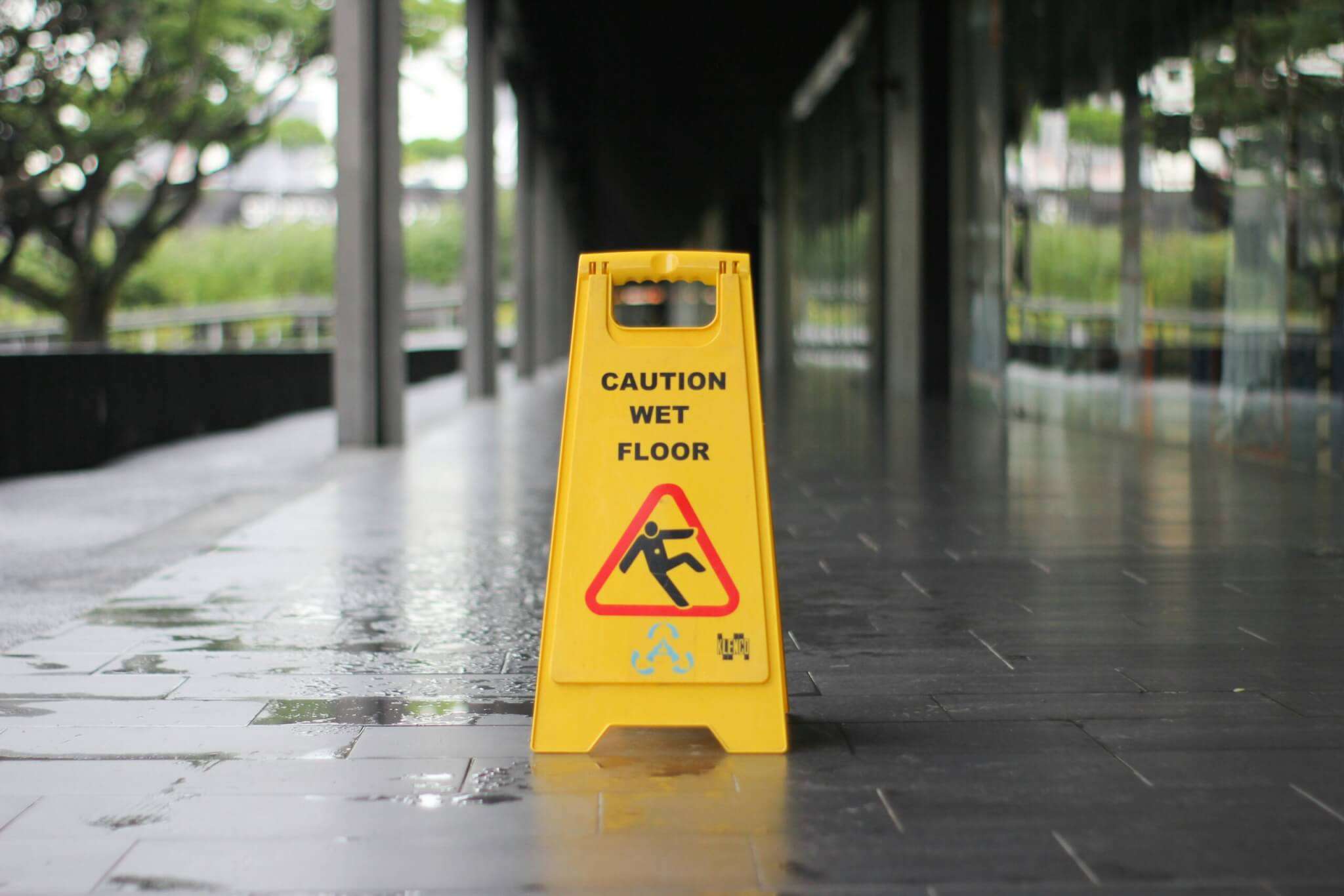 A bright yellow wet floor sing placed outside