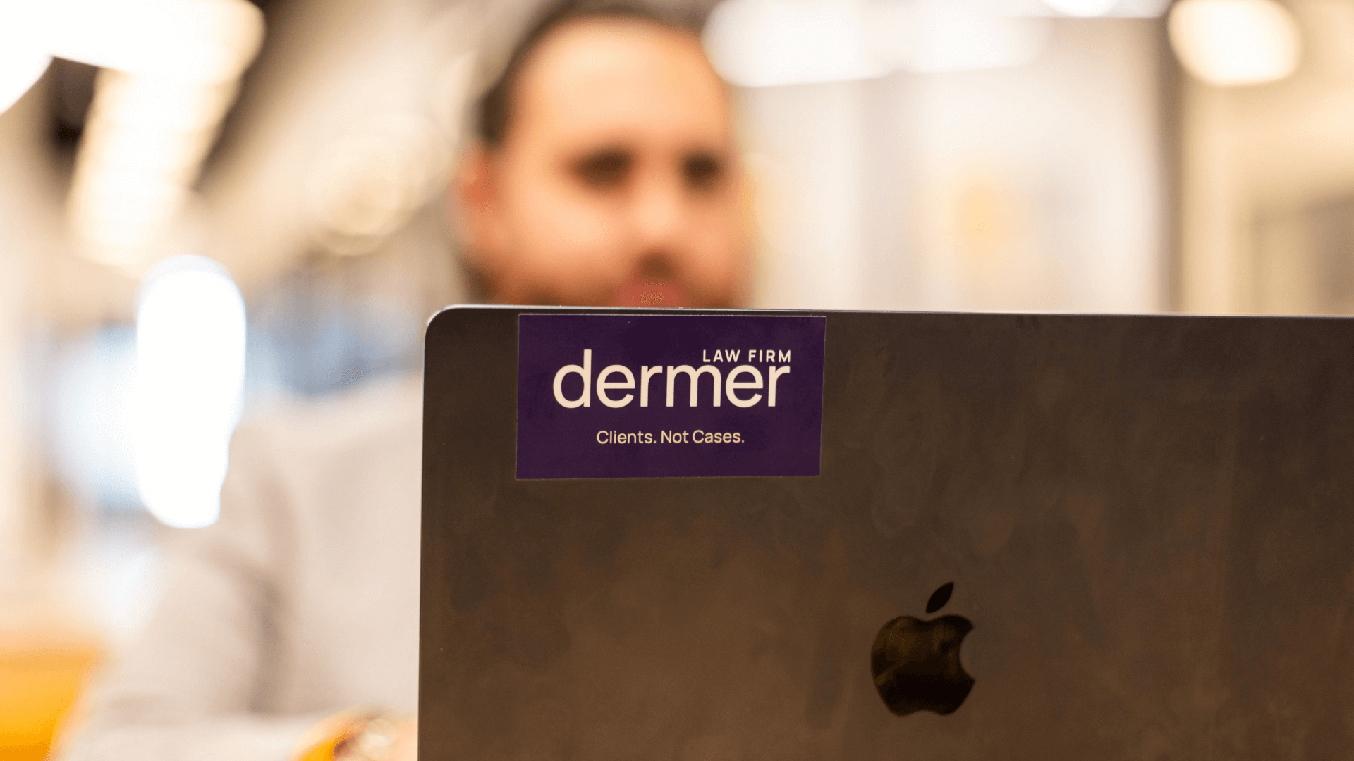 Man working on laptop with Dermer Law Sticker on laptop
