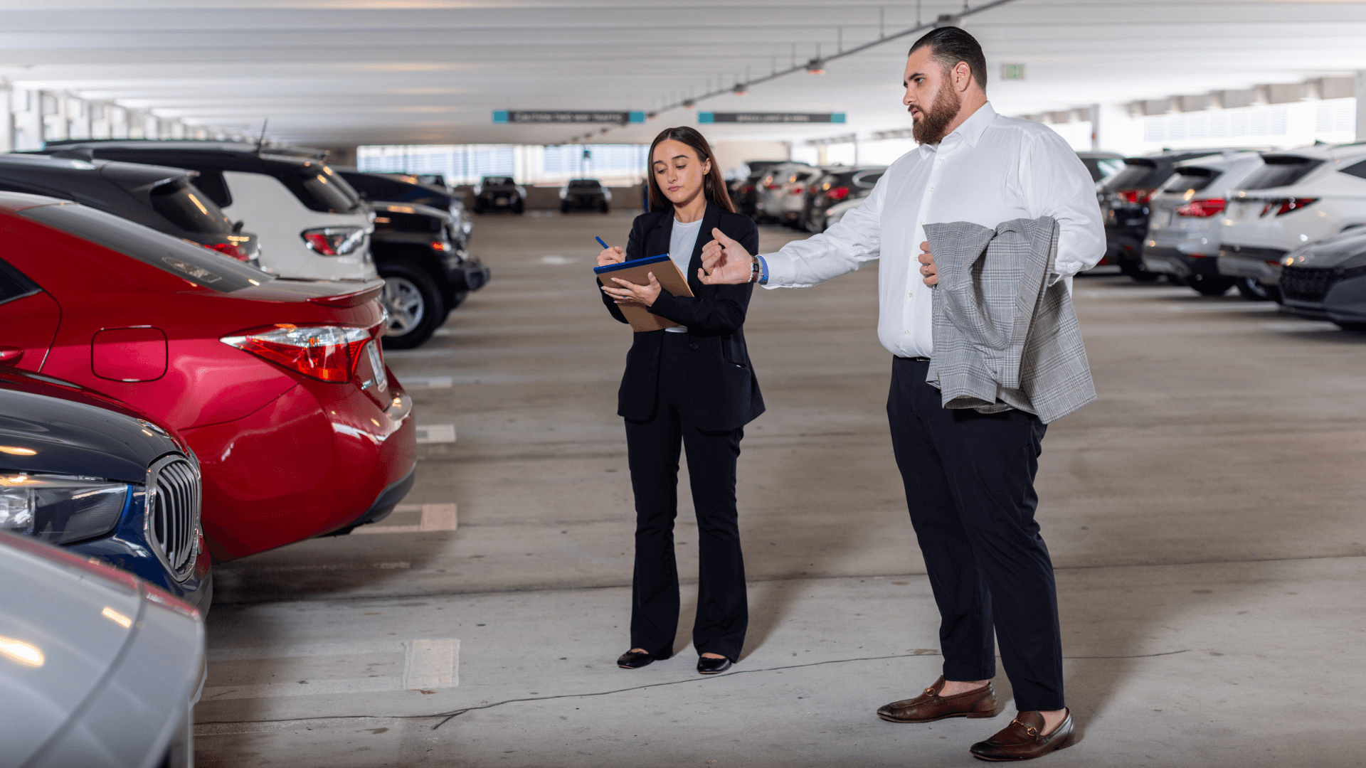 Jay Dermer is talking with a young lady in a parking garage as the young lady is taking notes