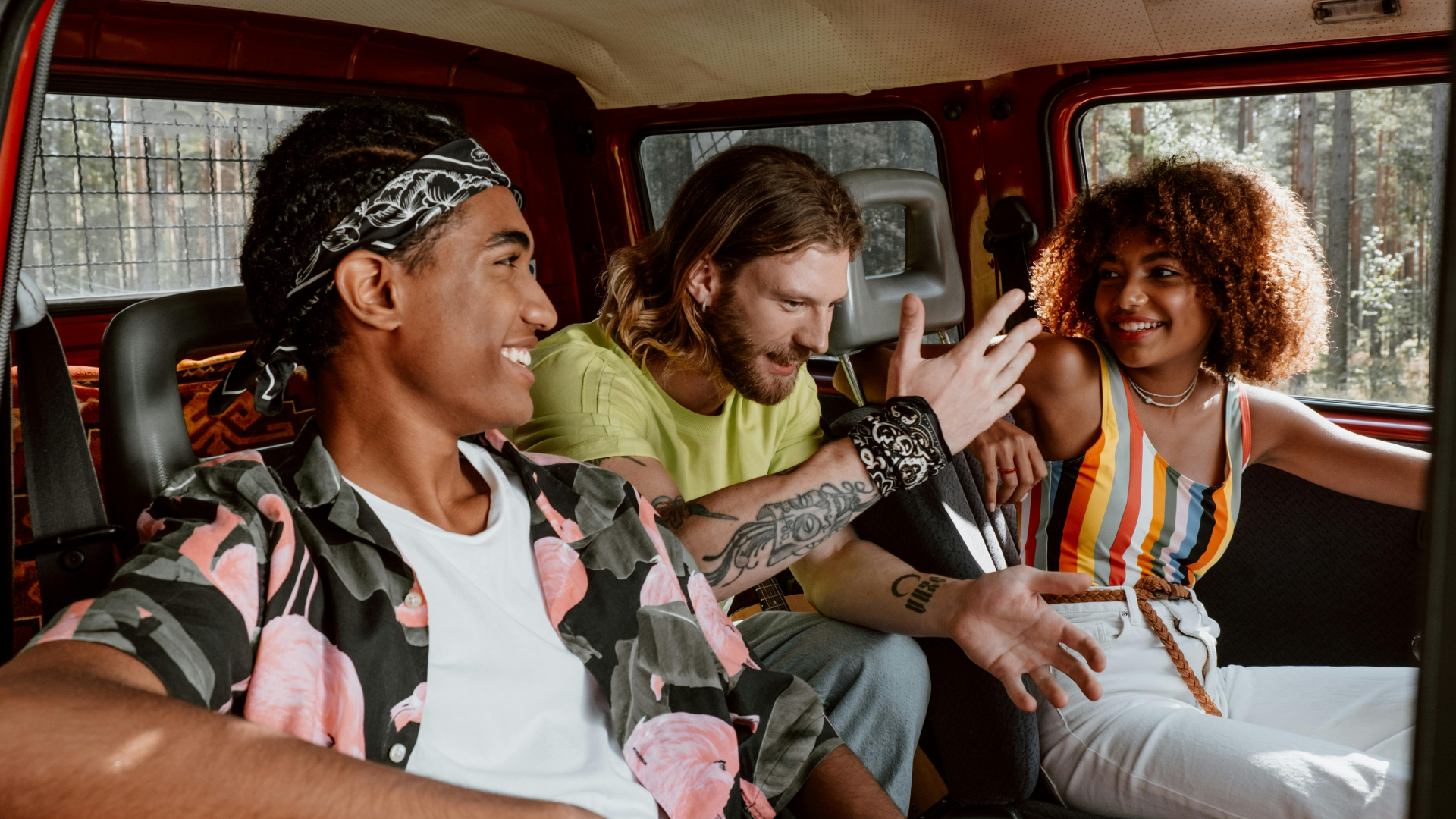 hree friends laughing and chatting inside a vehicle, enjoying a relaxed and cheerful moment.