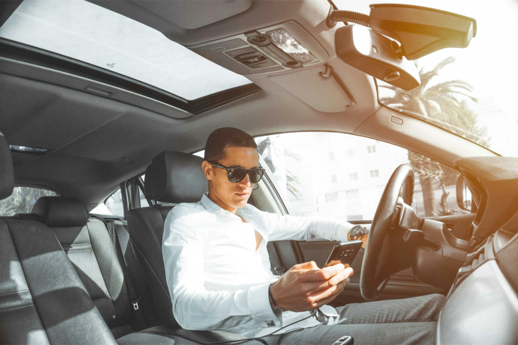 Man driving a car while looking at his phone, illustrating distracted driving.