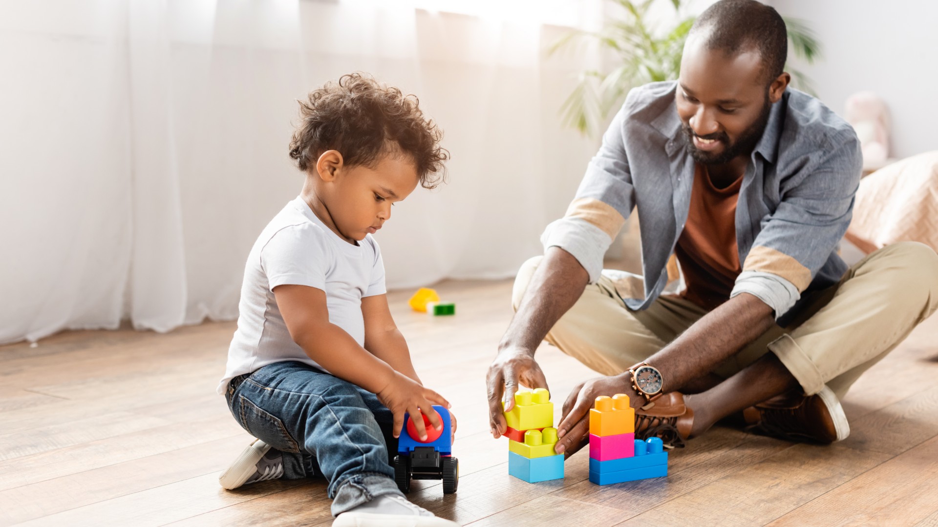 A young dad playing on the floor with his son