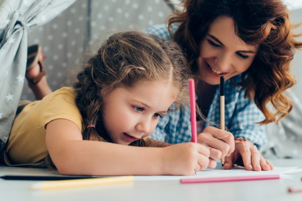 Adult and child drawing together with colored pencils on paper.
