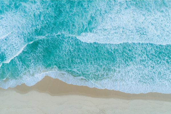 Aerial view of ocean waves rolling onto a sandy beach