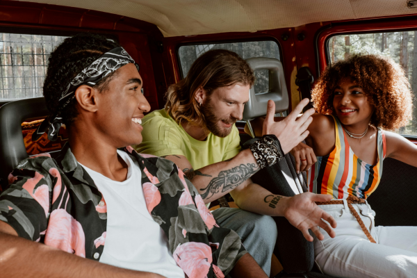 hree friends laughing and chatting inside a vehicle, enjoying a relaxed and cheerful moment.