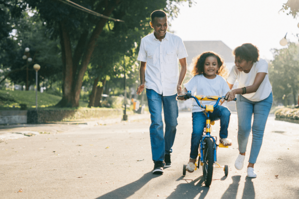 Una joven familia enseña a su hijo a montar en bicicleta