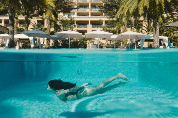 an underwater view of a person swimming in a clear, inviting pool.