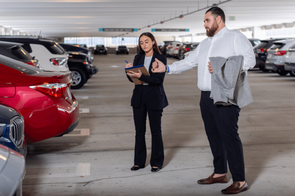 Jay Dermer is talking with a young lady in a parking garage as the young lady is taking notes