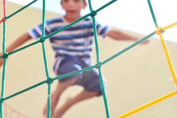 Child jumping on a trampoline behind a safety net.