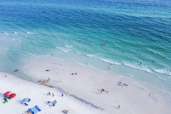 Vista aérea de bañistas nadando y descansando en una playa de arena blanca de Florida