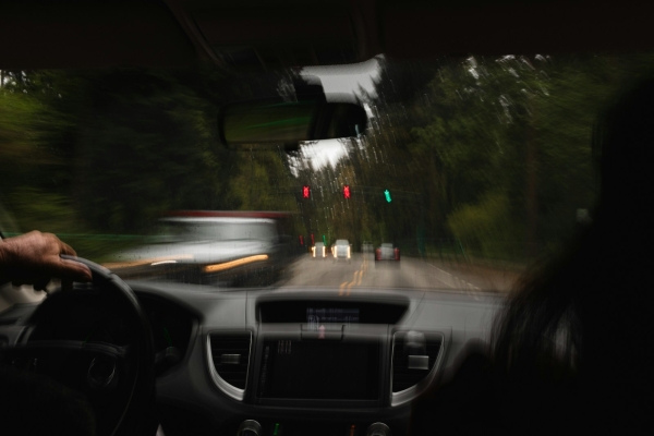 Vista del conductor a través del parabrisas mojado por la lluvia al acercarse a un semáforo