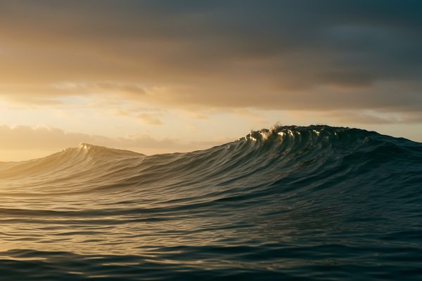 Ocean waves rolling beneath a dramatic golden sunset with sunlight reflecting across the water.