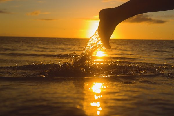 Chapoteando descalzo en el agua del mar al atardecer en Palm Beach Gardens, Florida