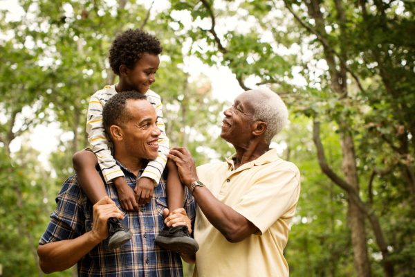 El abuelo, el padre y el nieto sonríen juntos al aire libre, simbolizando una familia formada gracias a la fecundación in vitro