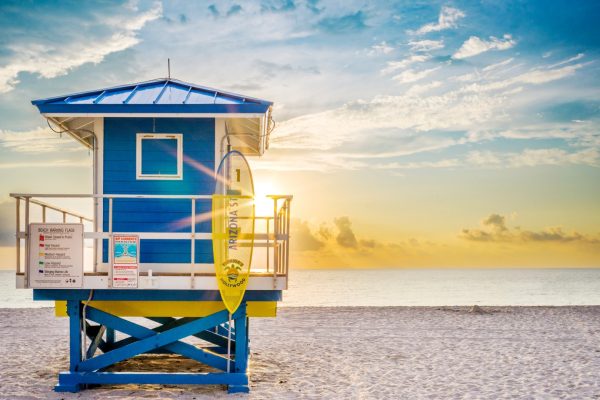 Torre azul de socorristas en una playa de Florida con una señal de seguridad que muestra una bandera de advertencia de playa